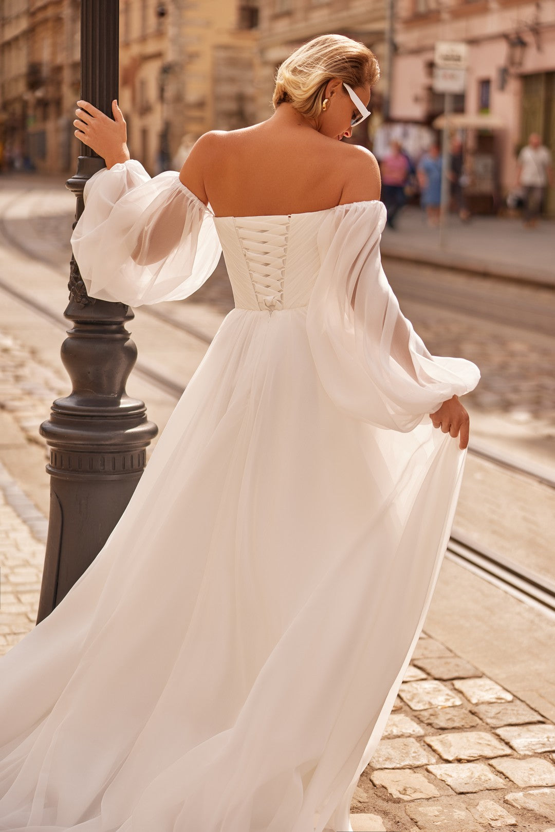 Bride wearing the Petra Wedding Dress – A-Line Bridal Gown with Corset & Sheer Sleeves and chapel