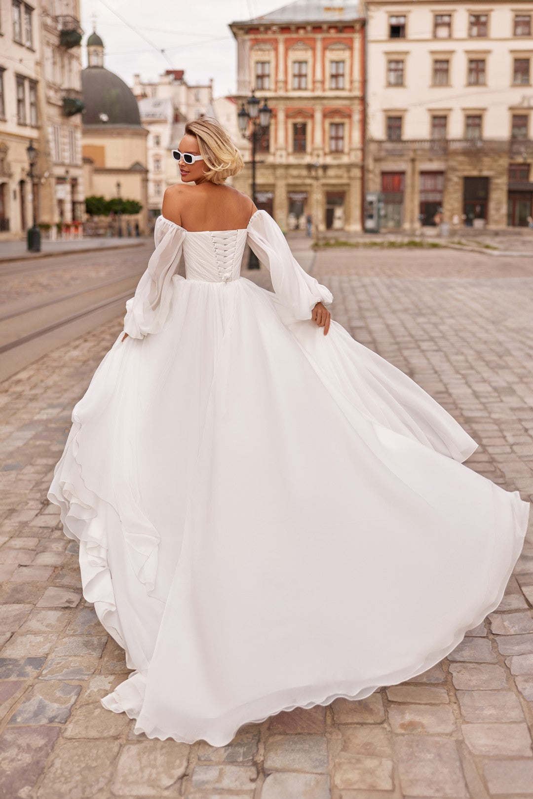 Bride wearing the Petra Wedding Dress – A-Line Bridal Gown with Corset & Sheer Sleeves and chapel